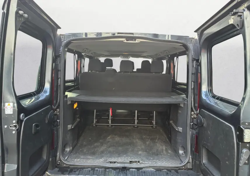 Vue arrière ouverte du Renault Trafic Combi gris foncé métal, montrant l'espace de chargement et les sièges arrière.