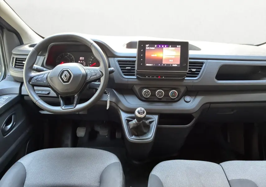 Vue frontale de l'intérieur du Renault Trafic Combi 2023, tableau de bord avec écran tactile et volant multifonction.
