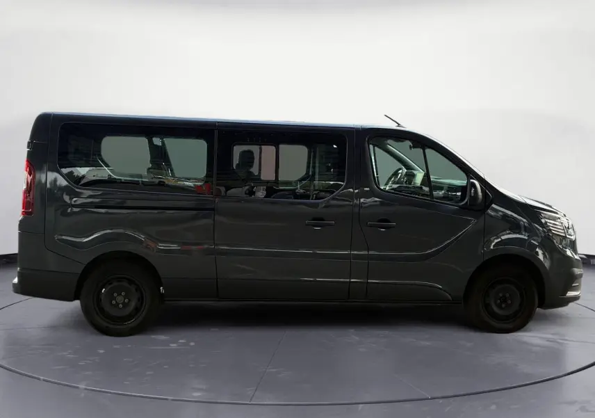 Profil latéral droit d'un Renault Trafic Combi gris foncé métallisé 2023 avec vitres teintées et roues acier noires.