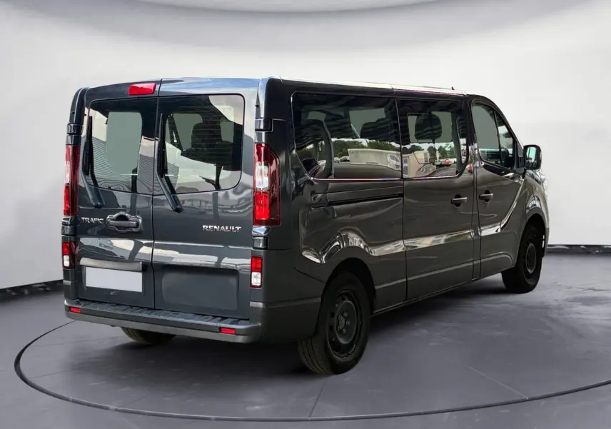 Vue 3/4 arrière droite d'un Renault Trafic Combi gris foncé métallisé, avec vitres latérales teintées et portes arrière battantes.