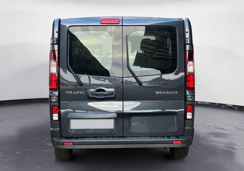 Vue arrière du Renault Trafic Combi gris foncé métallisé avec portes vitrées et essuie-glaces arrière visibles.
