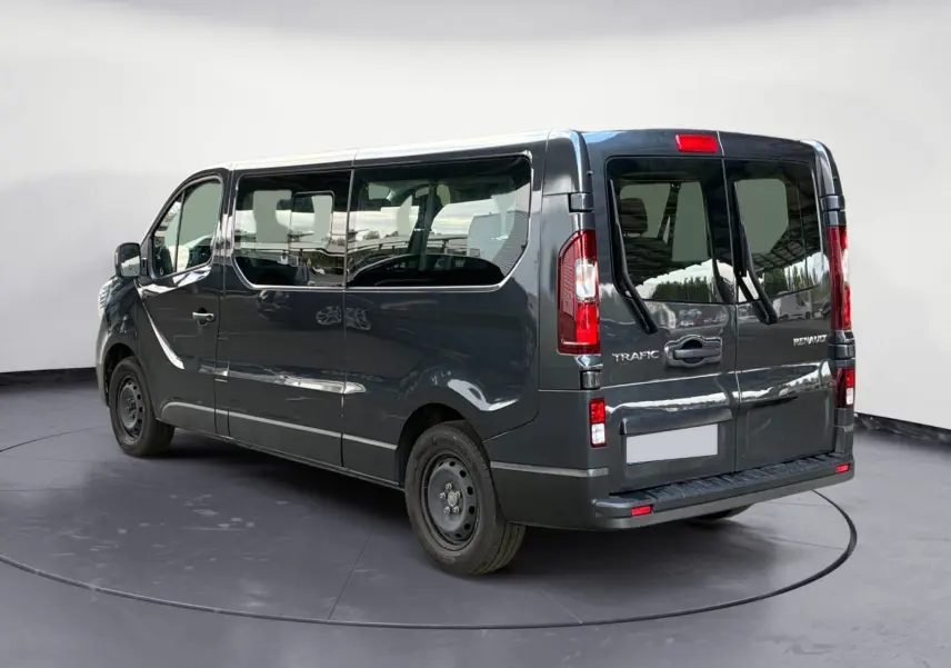 Vue 3/4 arrière droite d'un Renault Trafic Combi gris foncé métallisé avec vitres latérales teintées et hayon double.