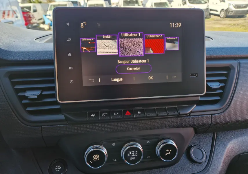 Vue rapprochée de l’écran tactile 8 pouces et de la console centrale du Renault Trafic Fourgon blanc, avec commandes climatisation et boutons fonctionnels.