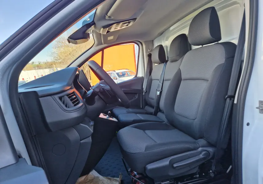 Vue intérieure côté conducteur du Renault Trafic Fourgon blanc 2025, montrant les sièges avant et le tableau de bord.
