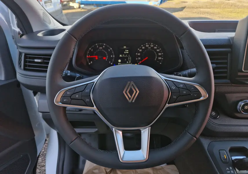 Vue rapprochée du volant noir du Renault Trafic Fourgon 2025 avec commandes intégrées et tableau de bord numérique.
