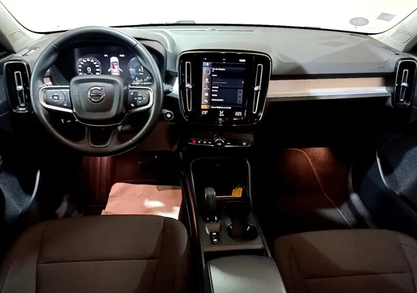 Vue intérieure frontale du tableau de bord noir du Volvo XC40 Recharge T4 avec écran tactile central et volant multifonctions.