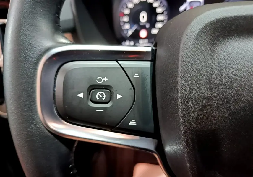 Gros plan sur les commandes de régulateur de vitesse au volant cuir noir du Volvo XC40 Recharge T4 Business 2020.