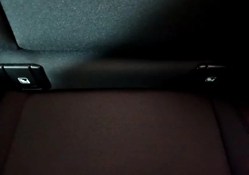 Détail de la banquette arrière noire du Volvo XC40 Recharge T4, montrant les commandes de rabattement des sièges.