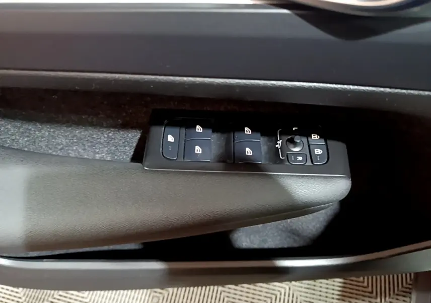 Gros plan sur les commandes des vitres électriques côté conducteur du Volvo XC40 Recharge T4 noir, intérieur sombre.