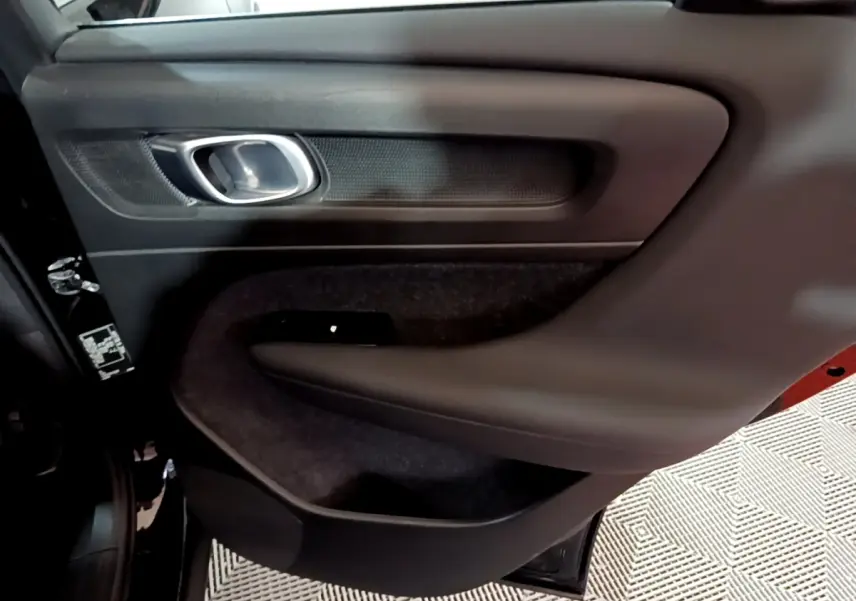 Gros plan sur la porte arrière gauche noire du Volvo XC40 Recharge T4, avec poignée argentée et garniture noire.