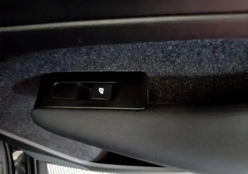 Gros plan sur le bouton de lève-vitre noir intégré à la garniture intérieure côté conducteur d'un Volvo XC40 noir.
