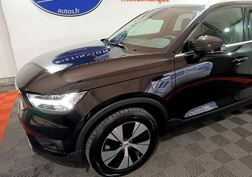 Vue 3/4 avant gauche du Volvo XC40 noir hybride rechargeable, mettant en valeur ses phares LED et jantes distinctives.