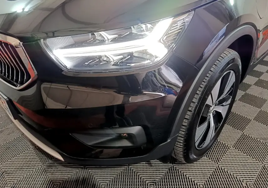 Gros plan sur l'avant droit noir du Volvo XC40 Recharge T4 avec phare LED et jante alliage distinctive.
