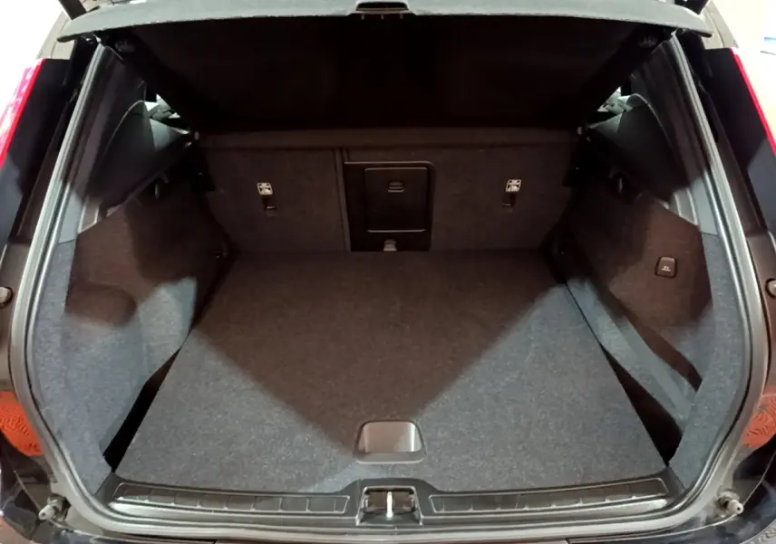 Coffre ouvert d'un Volvo XC40 noir, vue intérieure arrière montrant l'espace de chargement et revêtement gris.