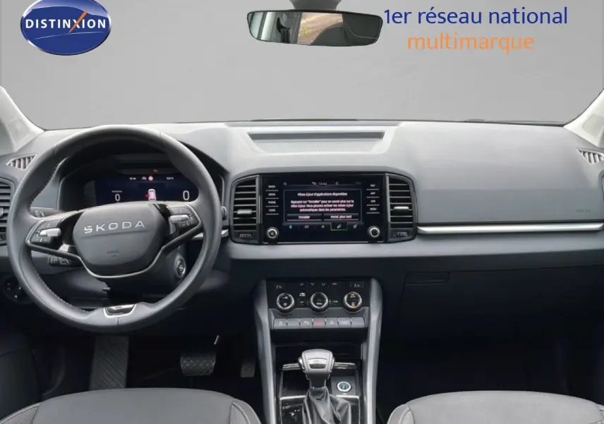 Vue intérieure avant du Skoda Karoq blanc glacier 2025, tableau de bord moderne avec écran tactile et volant cuir multifonction.