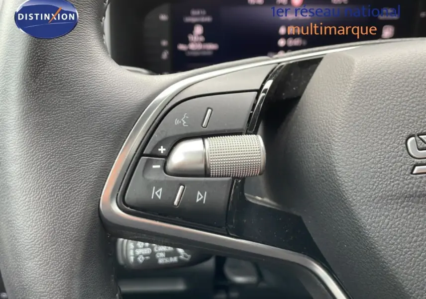 Gros plan sur les commandes au volant du Skoda Karoq blanc glacier 2025, mettant en valeur la molette et les boutons multifonctions.