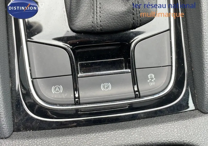 Gros plan sur les commandes de la console centrale noire du Skoda Karoq blanc glacier, mettant en valeur les boutons de frein à main et d'assistance.
