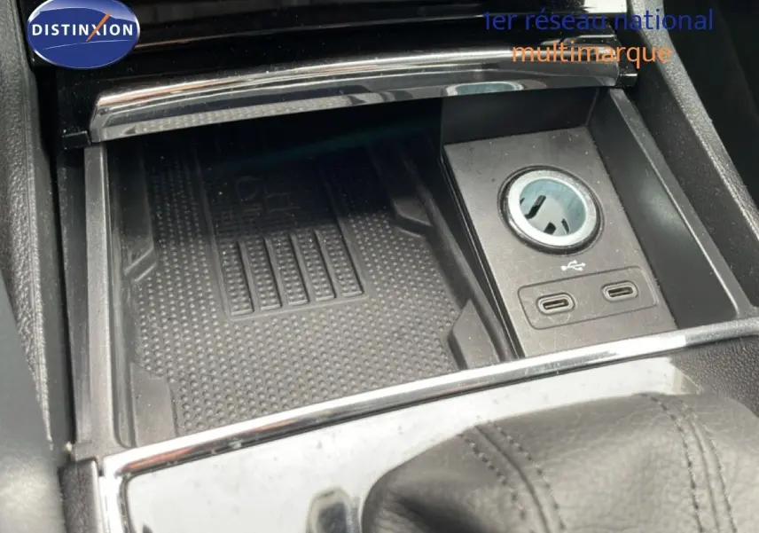 Gros plan sur la console centrale noire du Skoda Karoq blanc glacier, avec prise USB et allume-cigare visible.