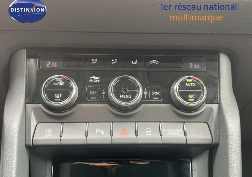 Gros plan sur la console centrale du Skoda Karoq blanc glacier, mettant en valeur les commandes de climatisation et les boutons de fonction.
