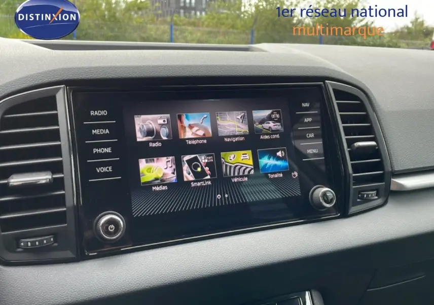 Écran tactile central du tableau de bord du Skoda Karoq blanc glacier, avec interface multimédia affichée.