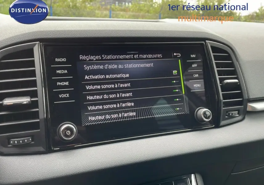 Vue rapprochée de l’écran central tactile du Skoda Karoq blanc glacier 2025 affichant les réglages d’aide au stationnement.