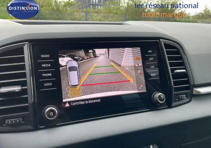 Écran central de la Skoda Karoq blanc glacier montrant la caméra de recul avec guidage de trajectoire coloré.