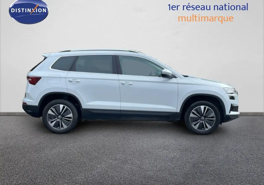 Vue de profil côté gauche d'un Skoda Karoq blanc glacier 2025 avec jantes bi-ton et toit ouvrant.