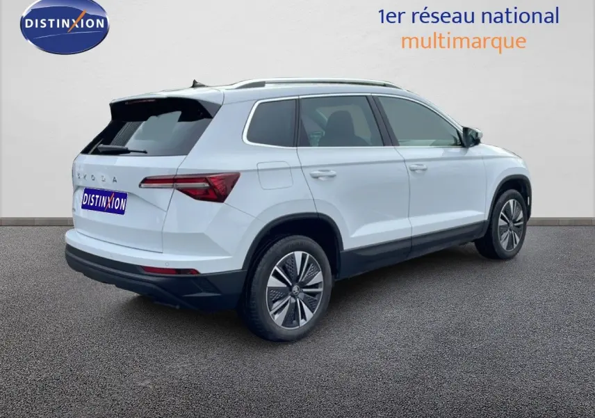SKODA KAROQ blanc glacier vu en 3/4 arrière droit, avec jantes bi-ton et vitres teintées.