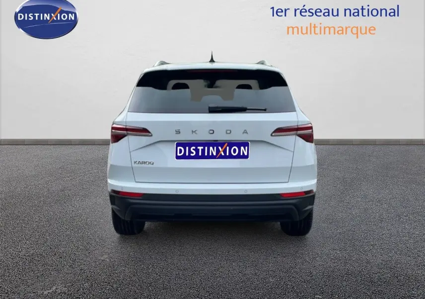 Vue arrière d'un Skoda Karoq blanc glacier 2025 avec feux arrière LED et logo SKODA visible.