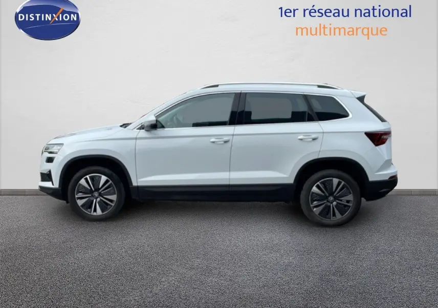 Vue de profil côté gauche d'un Skoda Karoq blanc glacier 2025 avec jantes bi-ton et toit surélevé.