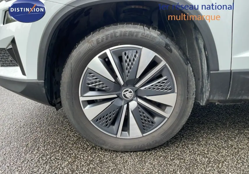 Gros plan sur la roue avant droite d’un Skoda Karoq blanc glacier avec jante alliage moderne.