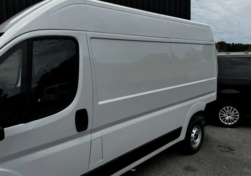 Vue de côté droit d’un Peugeot Boxer Fourgon blanc, version L2H1, avec porte latérale pleine et jante acier simple.
