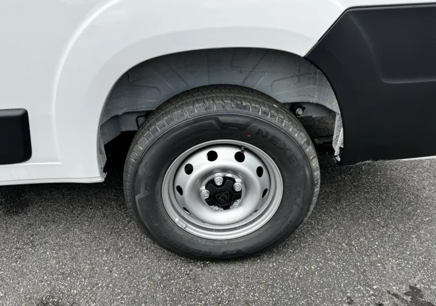 Gros plan sur la roue avant droite d’un Peugeot Boxer Fourgon blanc avec jante acier et logo Peugeot central.
