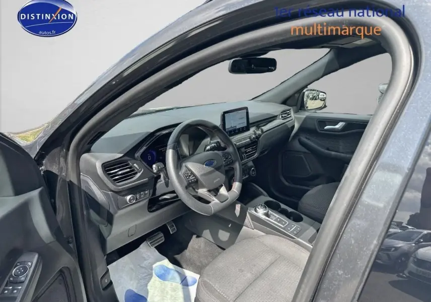 Intérieur gris foncé du Ford Kuga 2022 vu côté conducteur, avec tableau de bord moderne et écran tactile central.