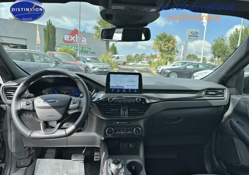 Vue intérieure avant du Ford Kuga 2022 gris foncé, montrant le tableau de bord avec écran tactile et volant multifonction.