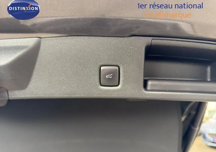 Bouton d'ouverture du coffre sur le hayon intérieur d'un Ford Kuga gris foncé, vue rapprochée.