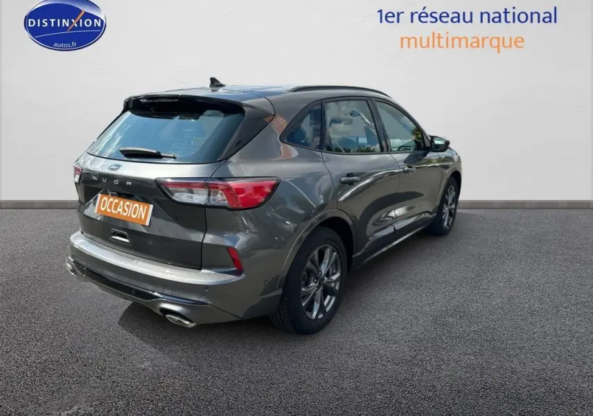 Vue 3/4 arrière droite d'un Ford Kuga gris foncé 2022 avec jantes alliage 18 pouces et attelage fixe visible.