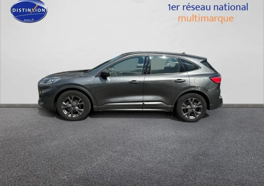 Ford Kuga gris foncé vue de profil côté gauche, avec jantes alliage 18 pouces et barres de toit visibles.