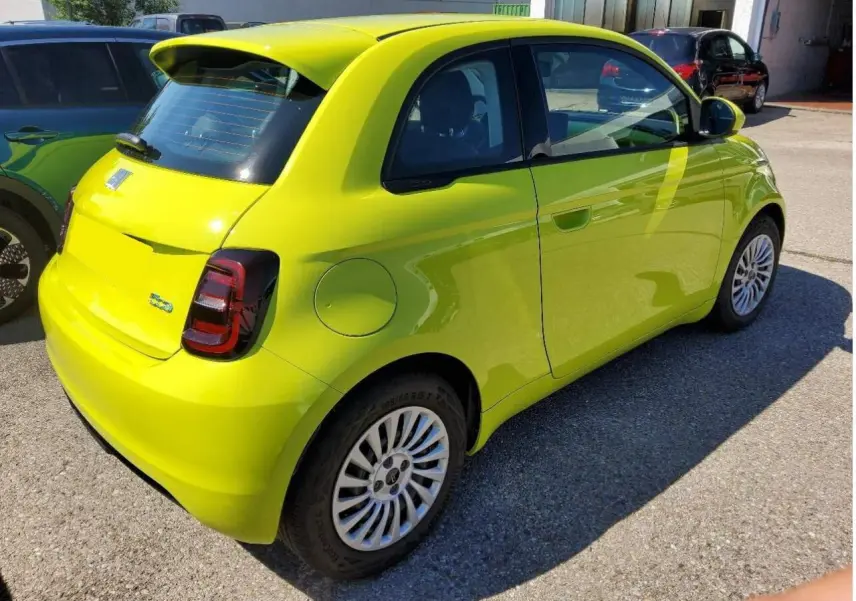 Fiat 500 électrique jaune Acid vue 3/4 arrière côté droit, avec feux arrière foncés et jantes blanches.