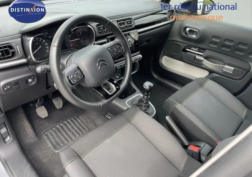 Intérieur de la Citroën C3 2021 en gris, vue côté conducteur montrant le tableau de bord et la boîte manuelle.