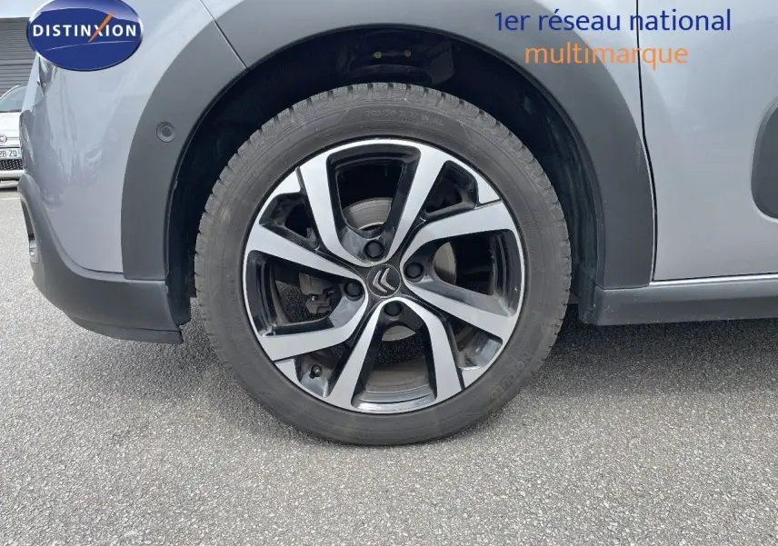 Gros plan sur la roue avant gauche de la Citroën C3 gris Artense métal avec jante alliage bicolore distinctive.