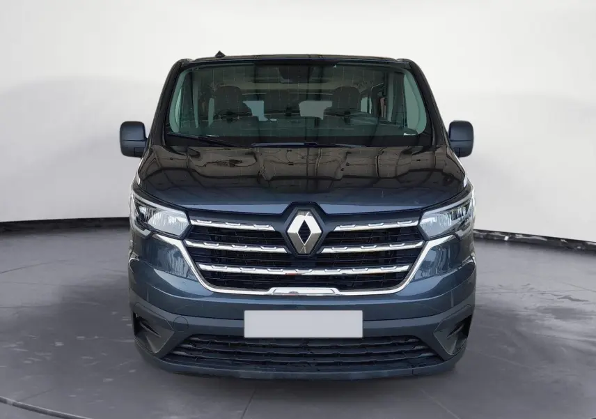 Vue frontale d'un Renault Trafic Combi gris foncé métal, mettant en valeur sa calandre chromée et son logo central.