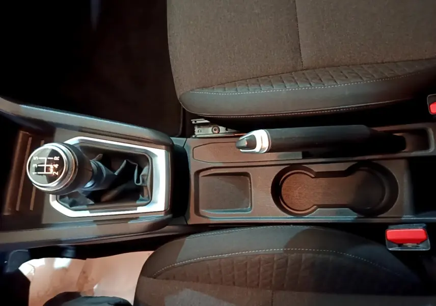 Vue plongeante sur la console centrale de la Renault Clio Business TCe 100, avec levier de vitesses manuel et frein à main entre sièges noirs.