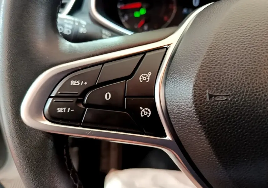 Gros plan sur les commandes du régulateur de vitesse au volant cuir noir de la Renault Clio Business blanche de 2019.