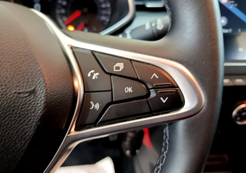 Gros plan sur les commandes multifonctions noires du volant cuir synthétique d'une Renault Clio Business blanc.