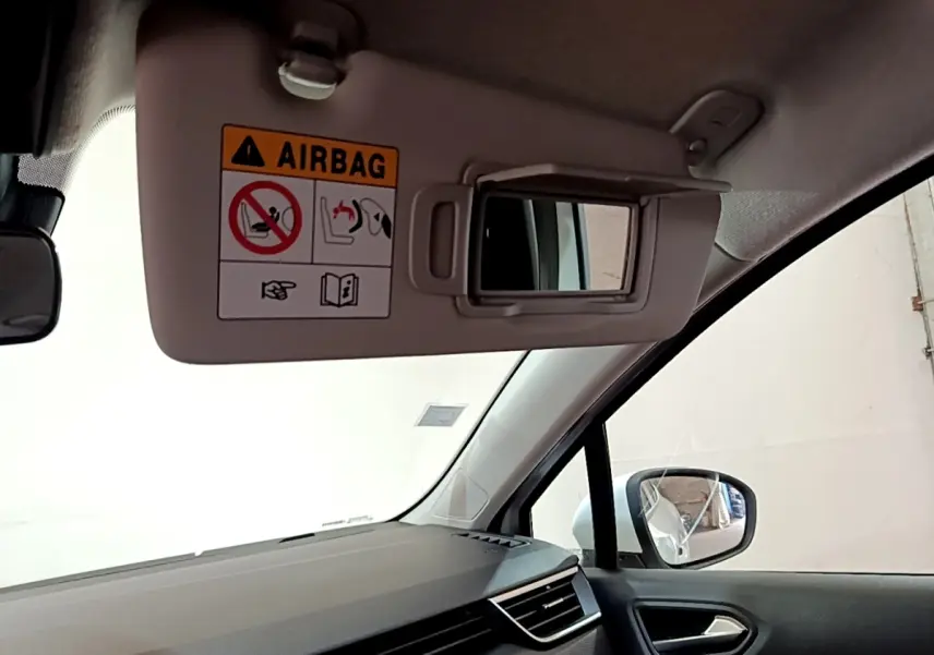 Détail du pare-soleil côté conducteur avec miroir et avertissement airbag dans une Renault Clio Business blanche de 2019.
