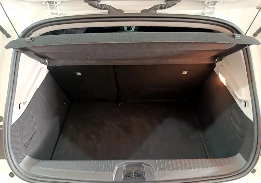 Coffre ouvert vu de l'arrière d'une Renault Clio Business TCe 100 blanche, montrant l'espace de chargement vide et la tablette de séparation.
