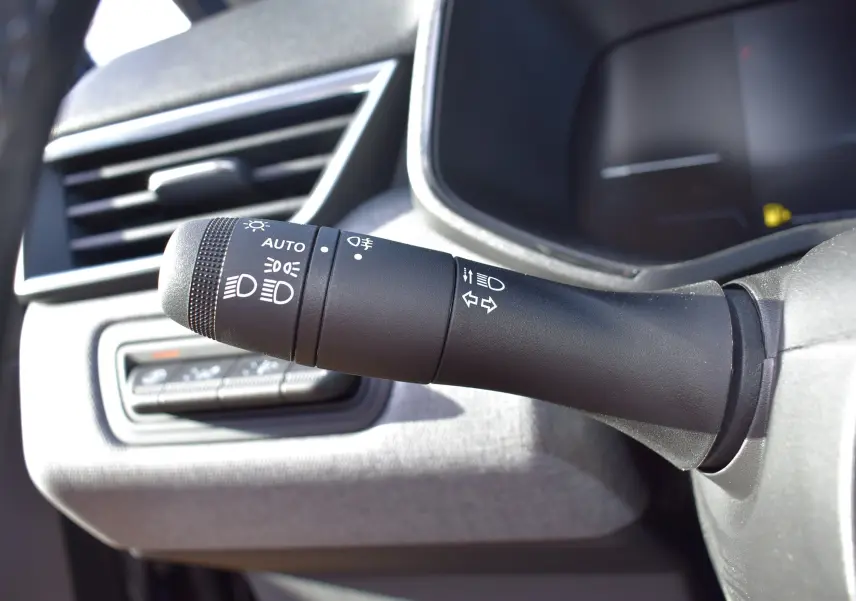 Gros plan sur la commande des phares et clignotants dans l’habitacle de la Renault Clio V TCe 90 noir, côté gauche du volant.