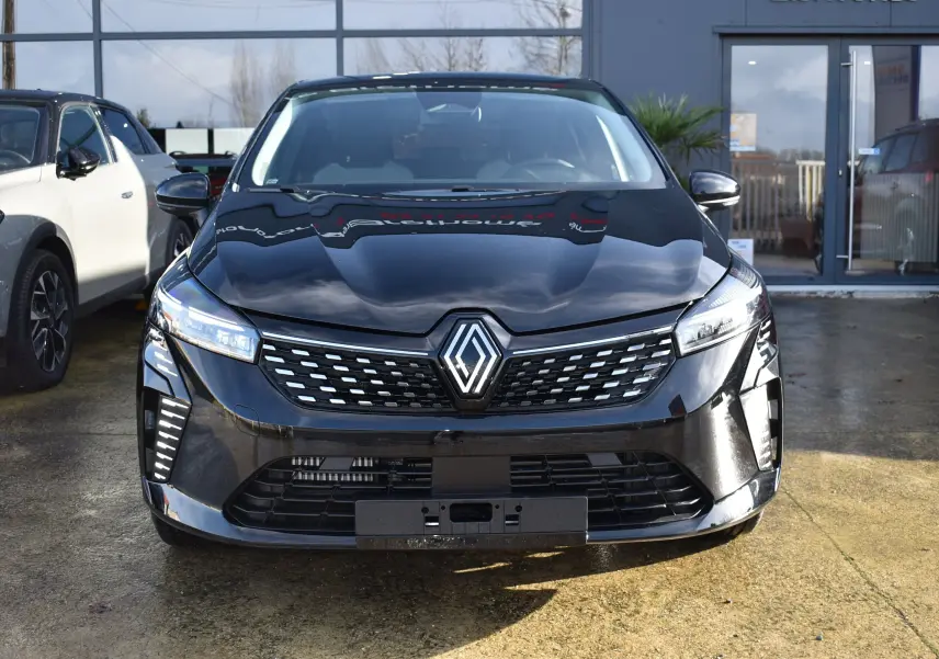 Vue avant d'une Renault Clio V TCE 90 noire 2025 avec calandre moderne et feux LED distinctifs allumés.