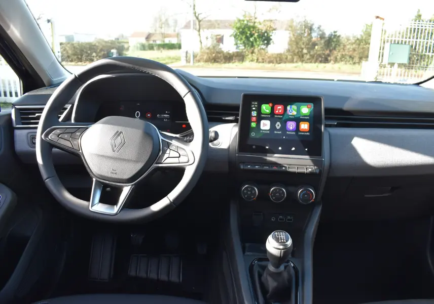 Vue intérieure avant de la Renault Clio V TCe 90 noire, avec volant multifonction, écran tactile et boîte manuelle à 6 vitesses.